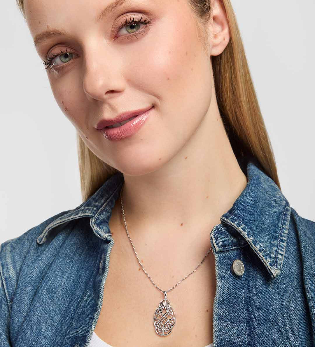 A close-up of a woman wearing an elaborate openwork Celtic necklace with beautifully interwoven knotwork, enhanced by a mix of polished silver and fine beaded detailing.