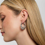 A model wearing large silver Claddagh hoop earrings, featuring the traditional Irish symbol of love, loyalty, and friendship