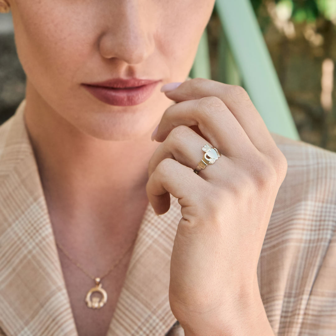 close-up image of woman wearing Claddagh ring in yellow gold
