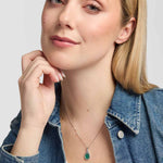 Model wearing an elegant teardrop pendant which showcases a rich green Malachite stone within a smooth polished silver frame, with an intricate Trinity Knot adding a distinctive Celtic finish.