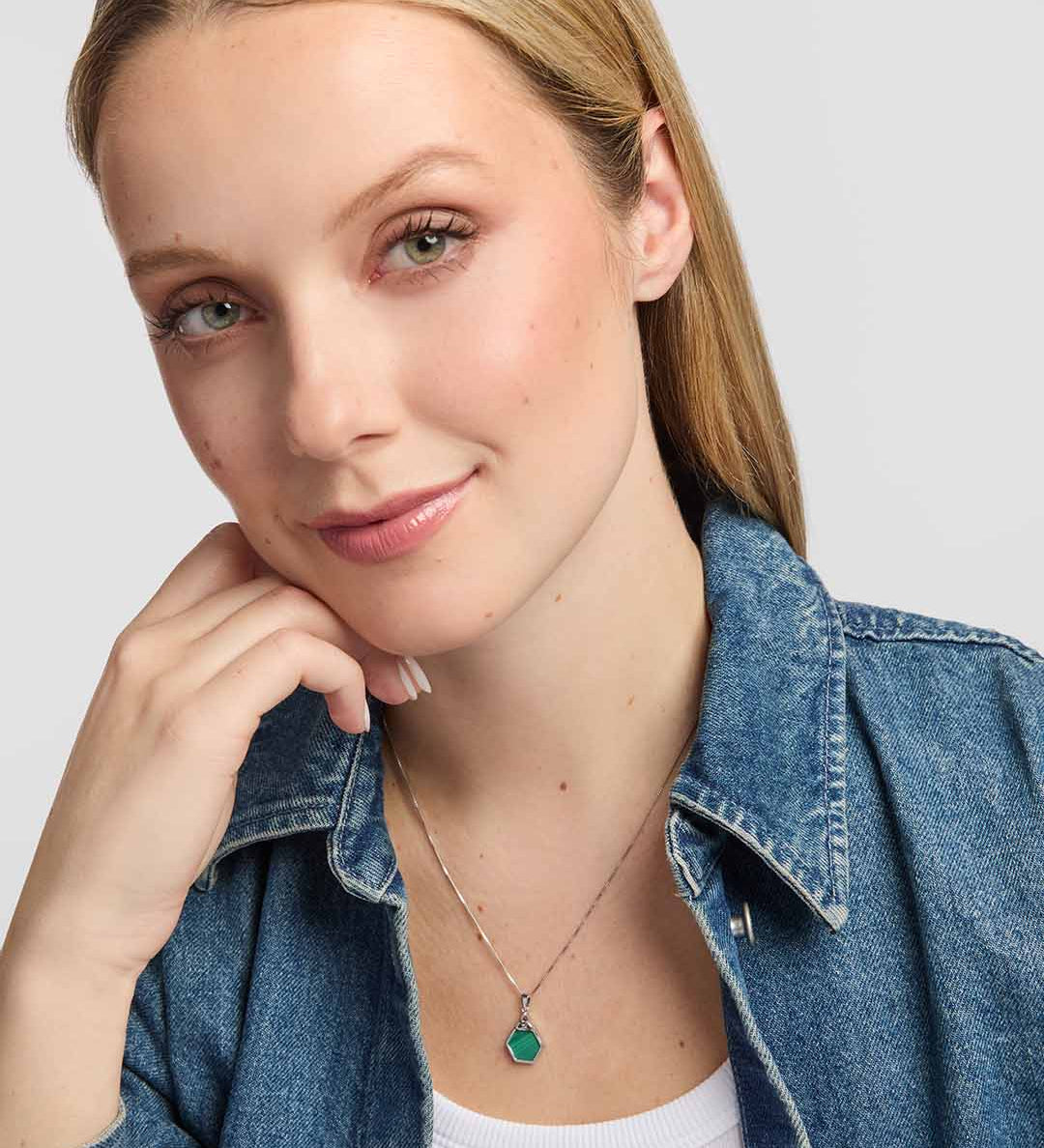 A striking green malachite stone framed in polished sterling silver, with an openwork Trinity Knot forming an elegant Celtic detail above the stone presented on a model