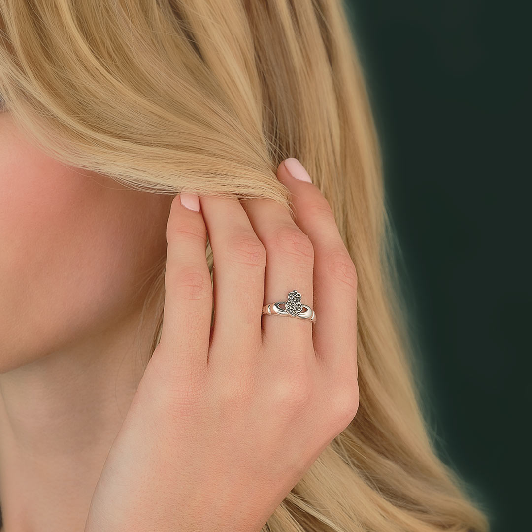 Close-up of a hand with silver marcasite Claddagh ring on a blurred background