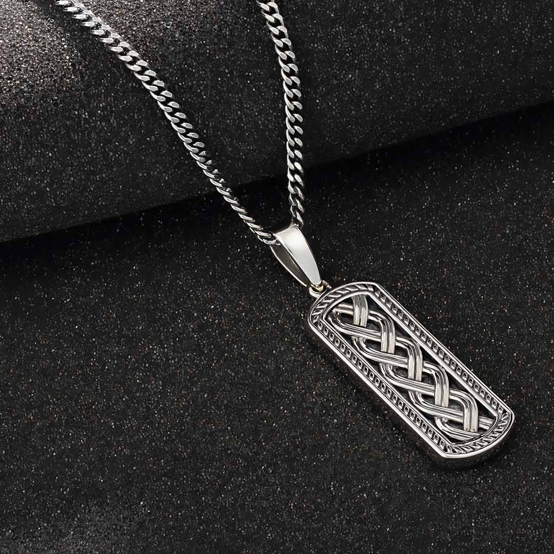 lifestyle image of silver mens celtic ingot pendant on dark background