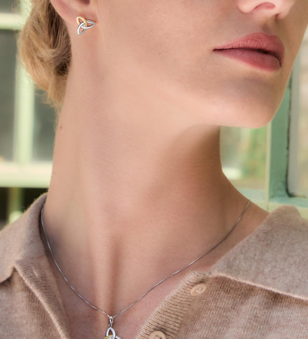 Close-up of a woman wearing Celtic Trinity Knot earrings and necklace set from Solvar