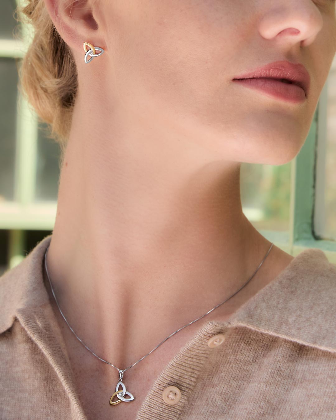 Close-up of a woman wearing Celtic Trinity Knot earrings and necklace set from Solvar
