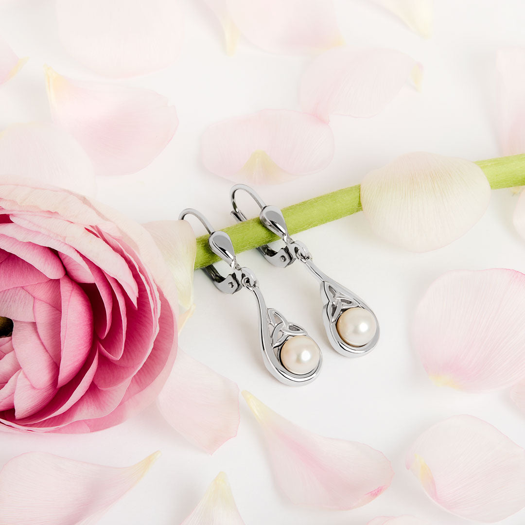 lifestyle image of Celtic pearl drop earrings on a floral background