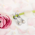 lifestyle image of Celtic pearl drop earrings on a floral background