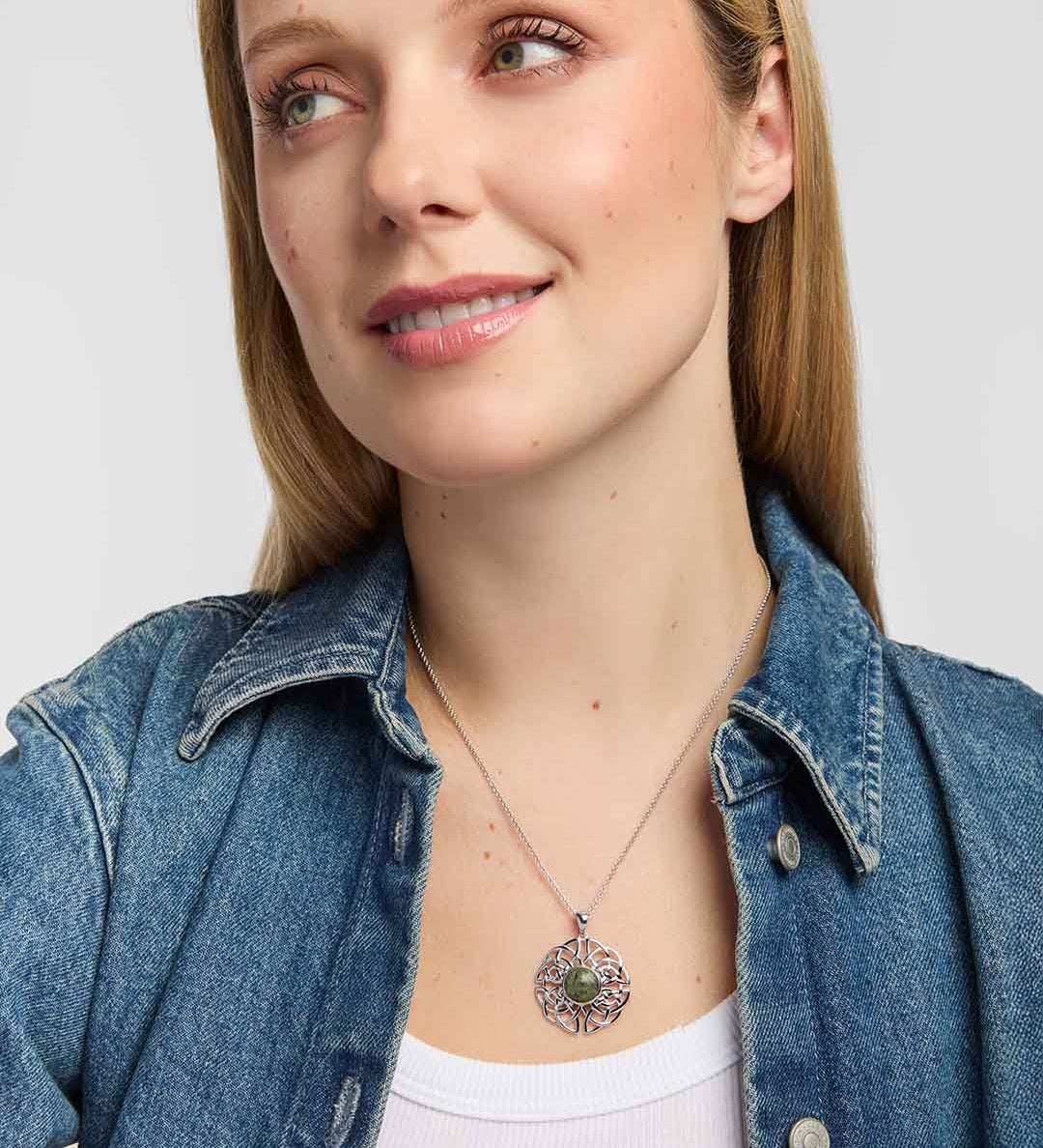 Model wearing Celtic Knot pendant with round Connemara marble centre framed by a polished silver-coloured setting and surrounded by intricate interwoven Celtic knotwork
