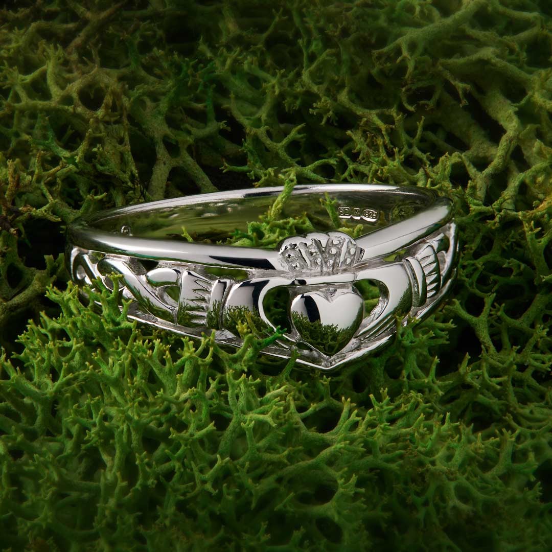 lifestyle image of silver Claddagh ring on green background