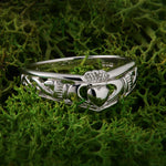 lifestyle image of silver Claddagh ring on green background