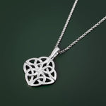 Silver Celtic knot pendant on a chain against a dark green background