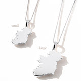 Two silver Ireland map pendant necklaces in small and large sizes, displayed side-by-side on a white surface with soft shadows
